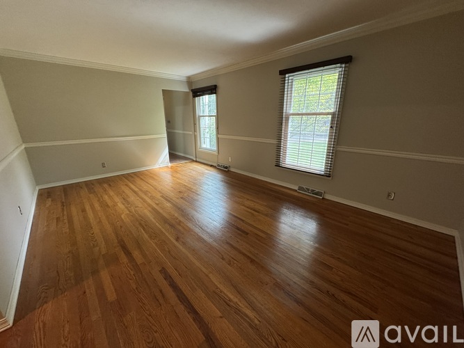 A room with wooden flooring and a window with blinds.