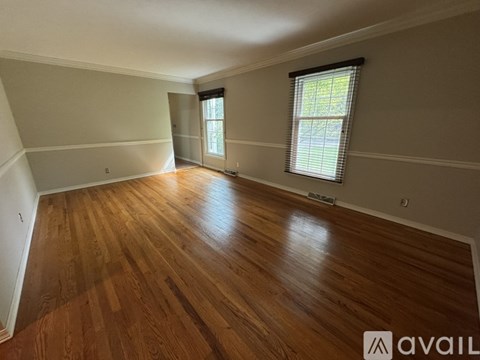 A room with wooden flooring and a window with blinds.