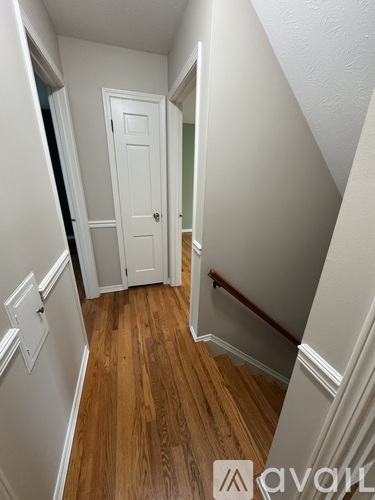 A hallway with wood floors and white walls.