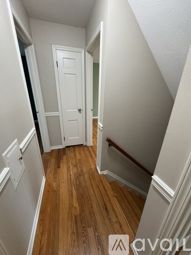 A hallway with wood floors and white walls.