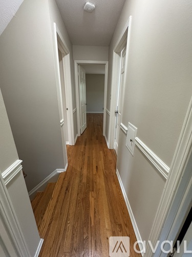 A hallway with wood floors and white walls.