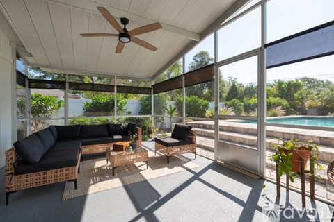 A patio with a ceiling fan and a view of a pool.