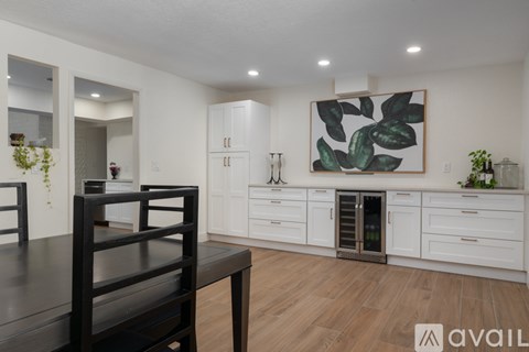 A modern kitchen with white cabinets and a wooden dining table.