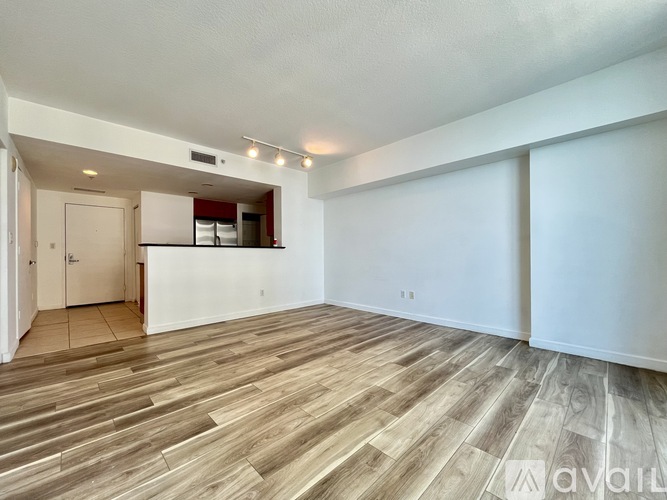 A spacious room with wooden flooring and white walls.