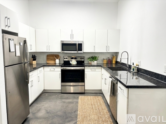 A kitchen with white cabinets and black countertops.