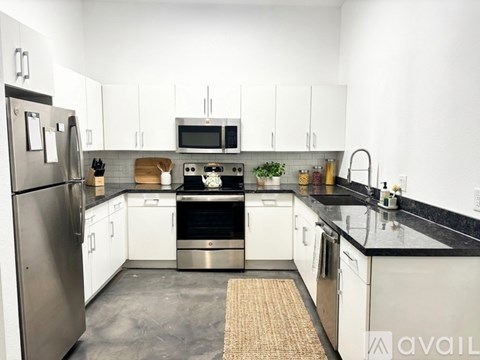 A kitchen with white cabinets and black countertops.