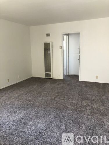 A room with a carpeted floor and a door on the right side.