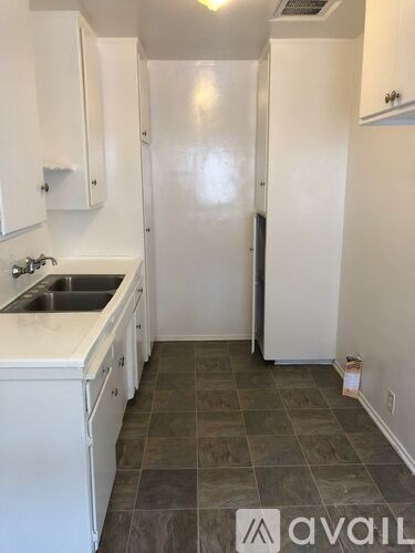 A kitchen with white cabinets and a tiled floor.