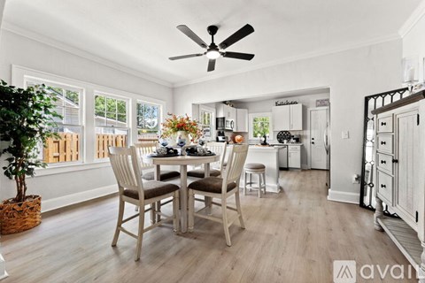 A dining room with a table set for four and a ceiling fan.