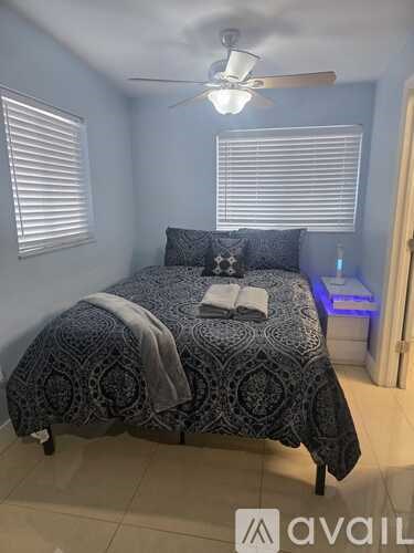 A bedroom with a patterned bedspread and a ceiling fan.