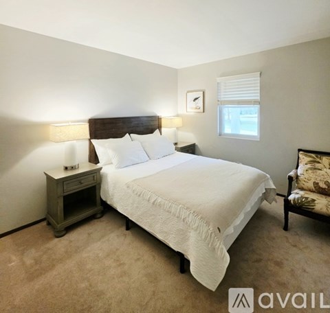 A bedroom with a bed, nightstand, and chair.
