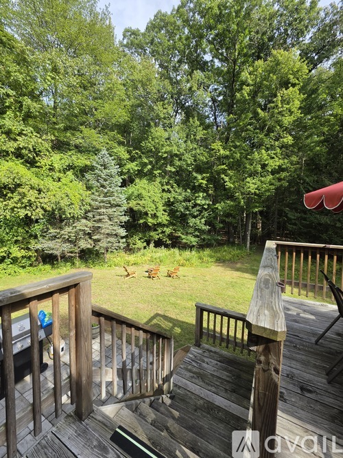 A deck with a railing and a view of a grassy area and trees.