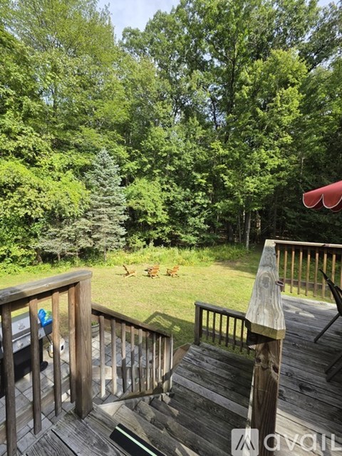 A deck with a railing and a view of a grassy area and trees.
