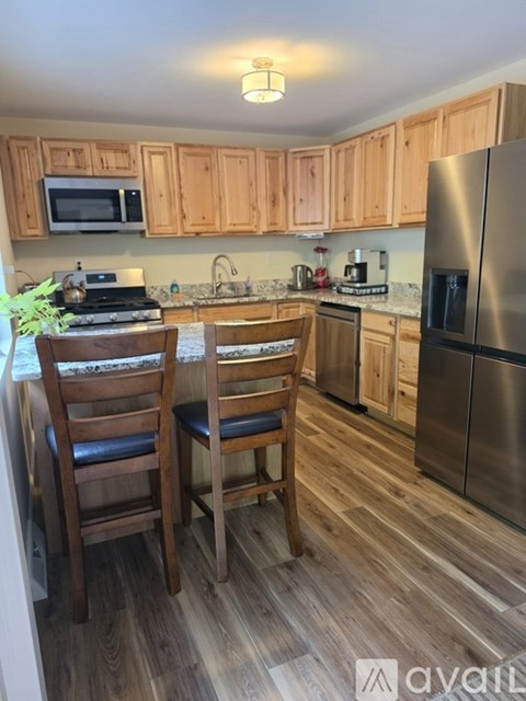 A kitchen with wooden cabinets and a stainless steel refrigerator.