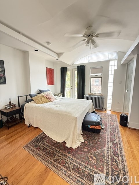 A bedroom with a bed, a rug, and a ceiling fan.