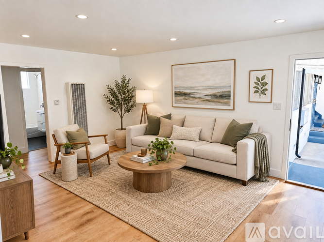 A living room with a white couch, a wooden coffee table, and a painting on the wall.