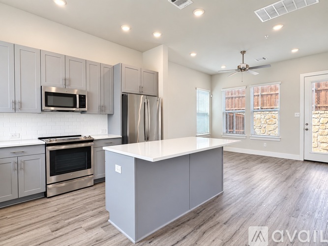 A kitchen with a white island and stainless steel appliances.
