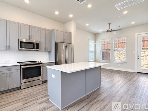 A kitchen with a white island and stainless steel appliances.