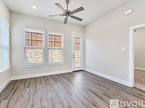 A room with a ceiling fan and three windows with stone designs.