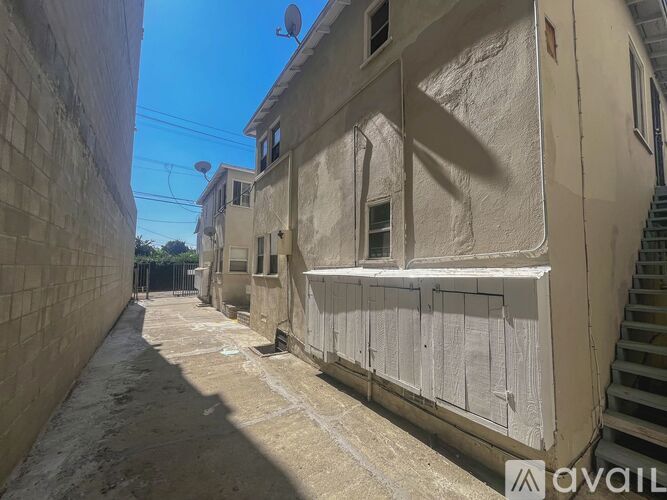 A narrow alley with buildings on either side and a satellite dish on the top floor.