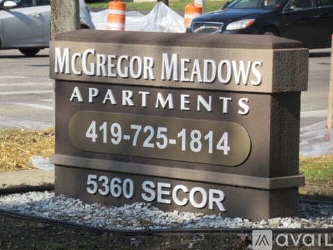 A sign for McGregor Meadows Apartments with a phone number and address.