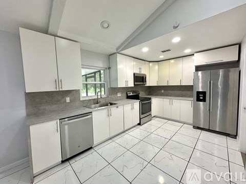 A kitchen with white cabinets and a marble floor.