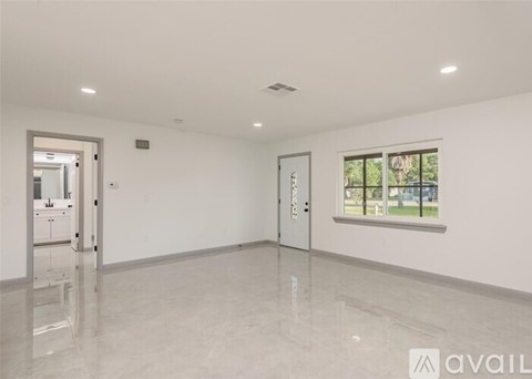 A spacious room with a large window and a view of trees outside.
