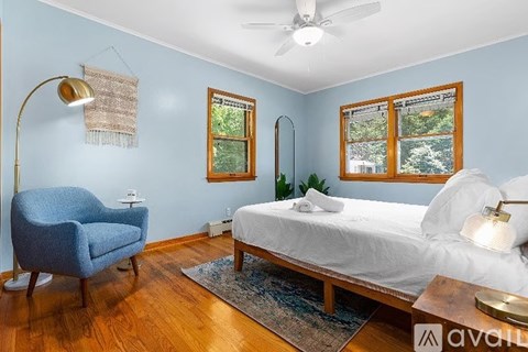 A bedroom with a bed, chair, and window.
