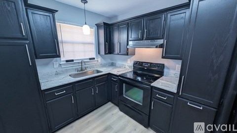 A kitchen with black cabinets and a wooden floor.