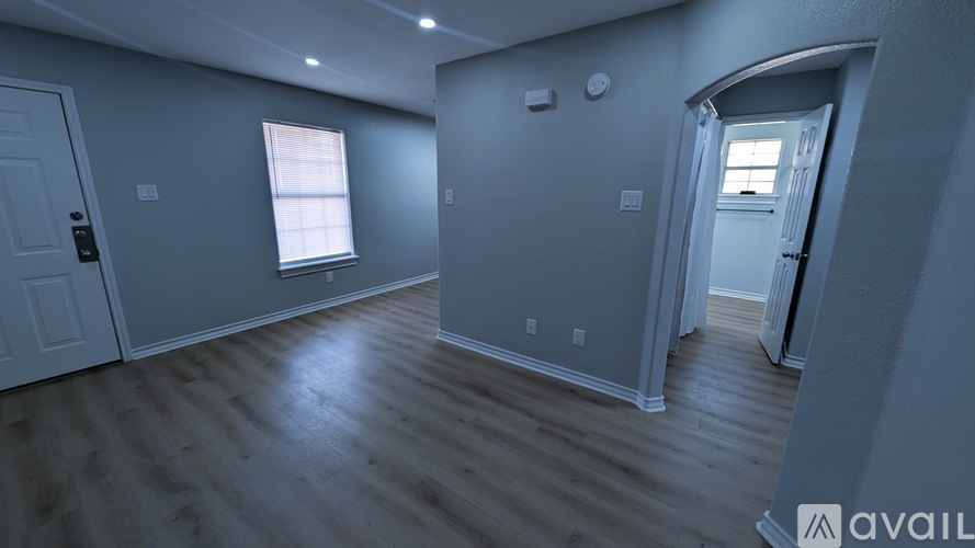 A spacious room with wooden flooring and a window.