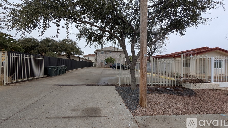 A tree stands in front of a building with a fence and a sign that says "available".
