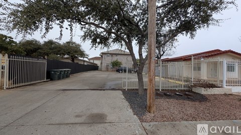 A tree stands in front of a building with a fence and a sign that says "available".
