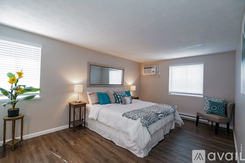 A bedroom with a bed, two lamps, a chair, and a vase of flowers.