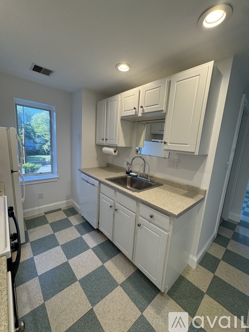 A kitchen with white cabinets and a checkered floor.