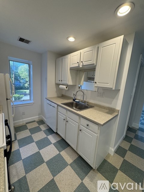 A kitchen with white cabinets and a checkered floor.