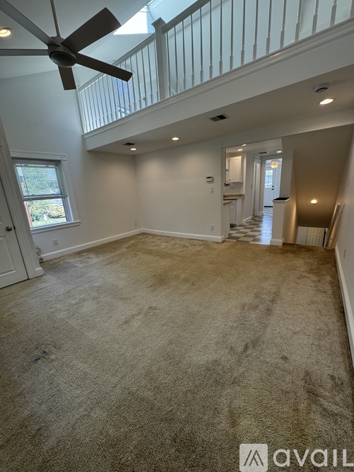A spacious room with a fan and carpeted floor.