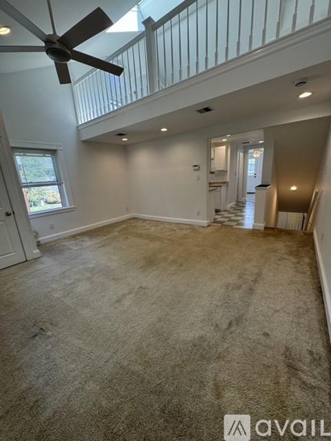 A spacious room with a fan and carpeted floor.