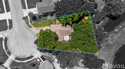 An aerial view of a property with a house, trees, and a body of water.