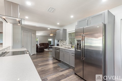 A modern kitchen with a stainless steel refrigerator and wooden flooring.