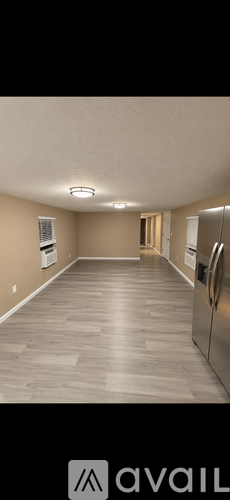 A spacious kitchen with a refrigerator and a door leading to another room.