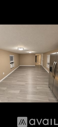 A spacious kitchen with a refrigerator and a door leading to another room.