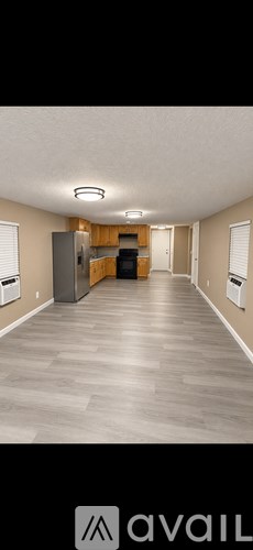 A spacious room with a kitchen area in the background.