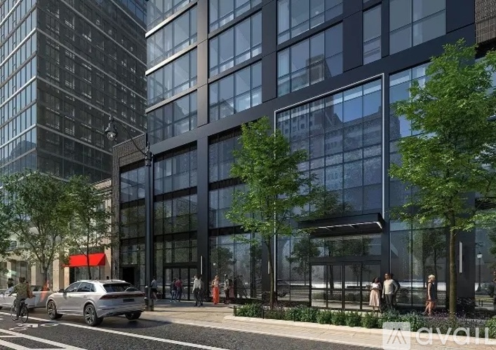 A modern building with a glass facade and a tree in front of it.