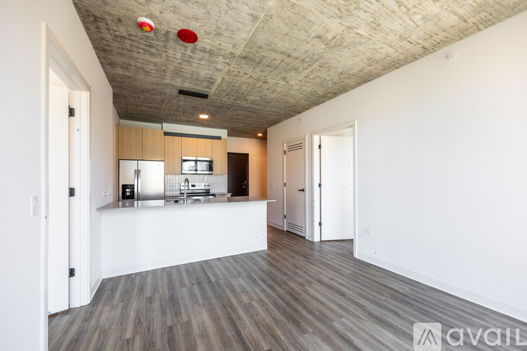 A kitchen area with a white counter and wooden flooring.