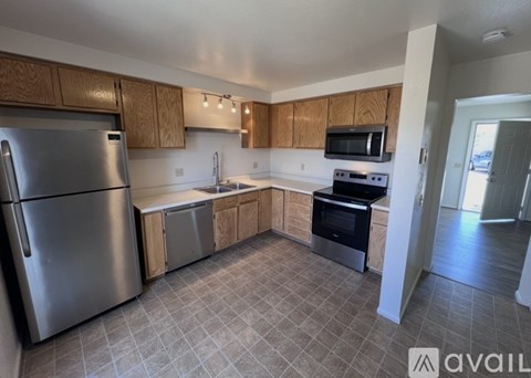 A kitchen with a refrigerator, microwave, oven, and sink.
