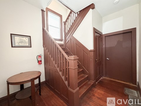 A wooden staircase with a round table and a fire extinguisher on the wall.