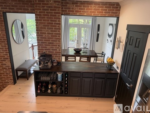 A kitchen with a black cabinet and a brick wall.