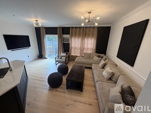 A living room with a grey couch and a television on the wall.