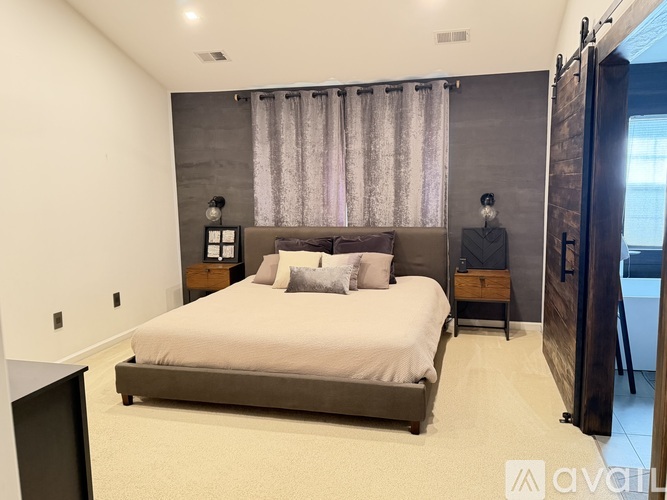 A bedroom with a large bed and a window with curtains.