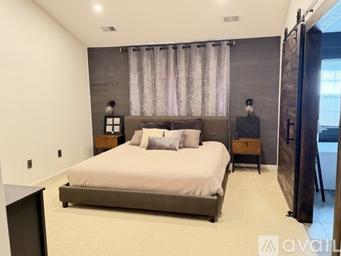 A bedroom with a large bed and a window with curtains.